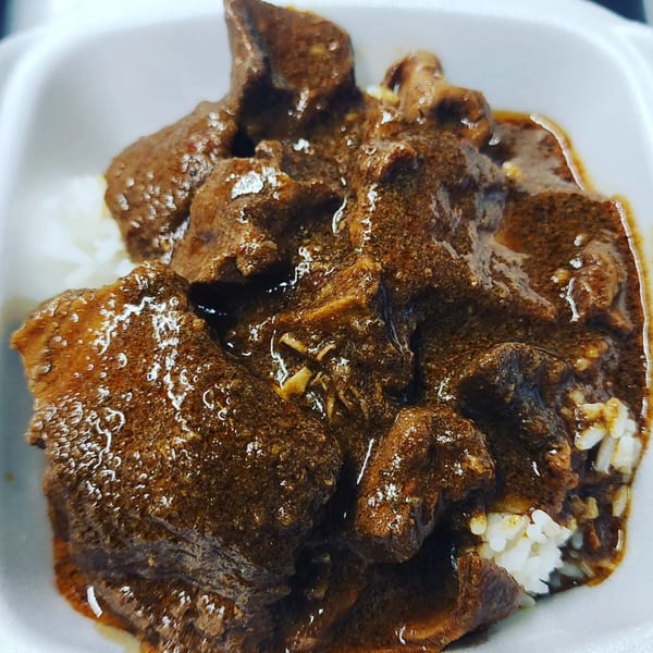 Close-up of JB's Cruisin Cuisine's soul food, featuring dark stewed meat over white rice.