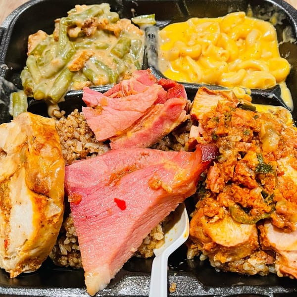 A soul food platter with green beans, mac and cheese, chicken, and sliced meat over rice.